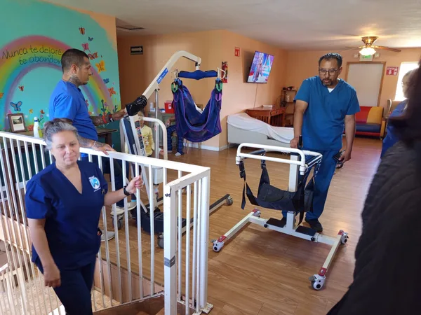 Alumnos aprendiendo a usar la grúa de traslado de pacientes en una casa de reposo