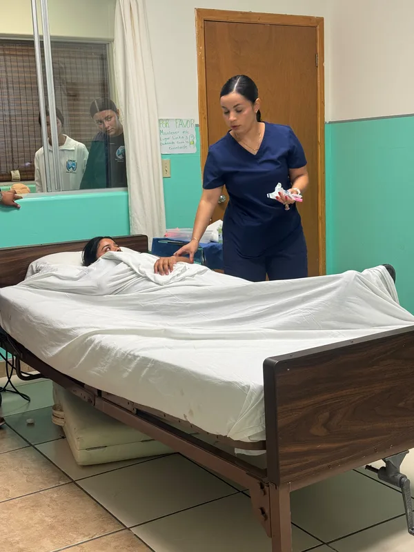 Alumna tendiendo la cama de hospital del laboratorio