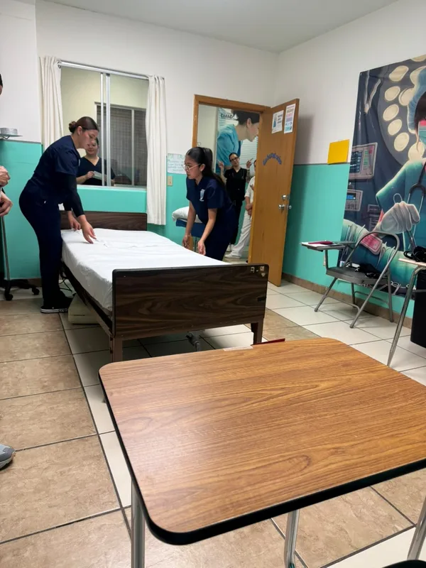 Laboratorio de prácticas con camas de hospital y mesa de trabajo